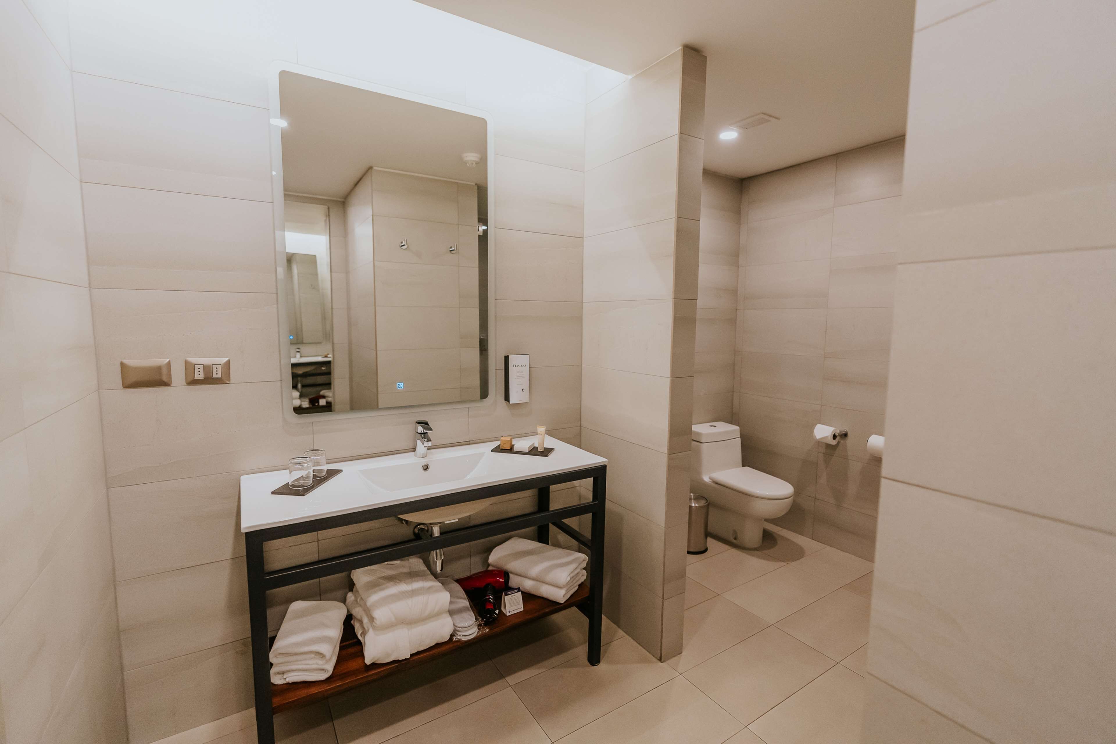 Une salle de bain moderne avec un lavabo blanc, un miroir, des toilettes et un espace douche.