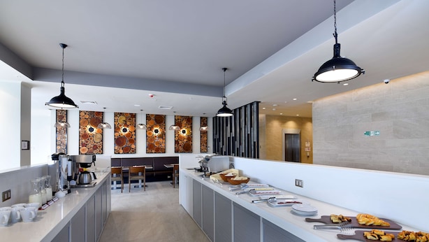Una cocina de hotel moderna con una barra larga, una cafetera y diversos alimentos.