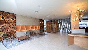 Un vestíbulo moderno con pared de madera, zona de estar y mostrador de recepción.