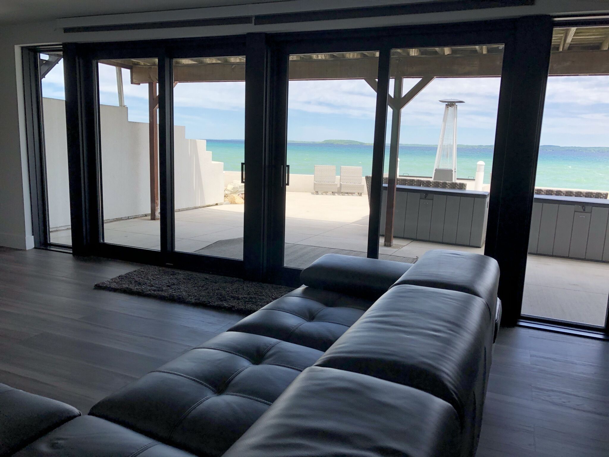 Ein modernes Wohnzimmer mit einer großen SchiebeglasTür, die auf einen Balkon mit Meerblick führt.