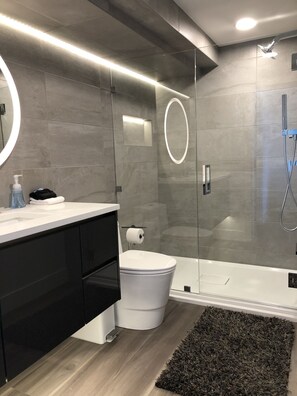 Een moderne badkamer met toilet, wastafel en douche.