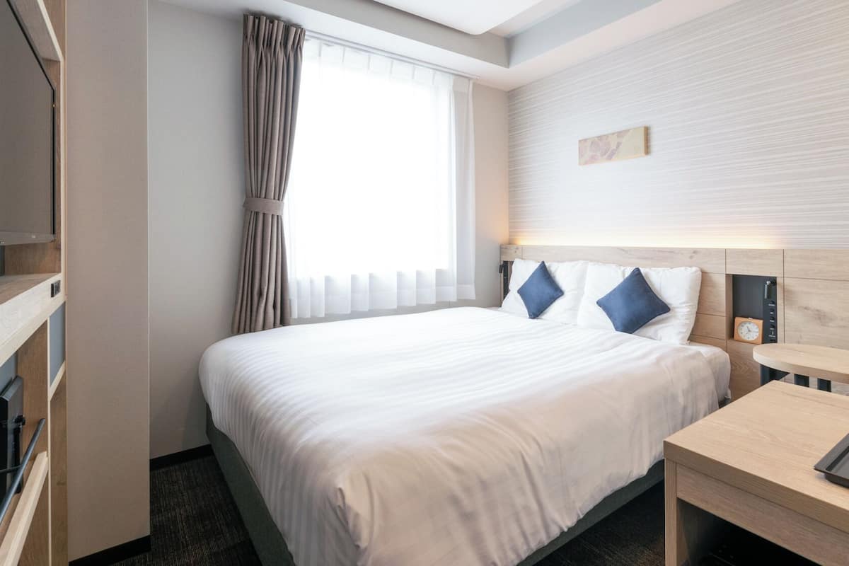 A hotel room with a large bed, bedside table, and a television.