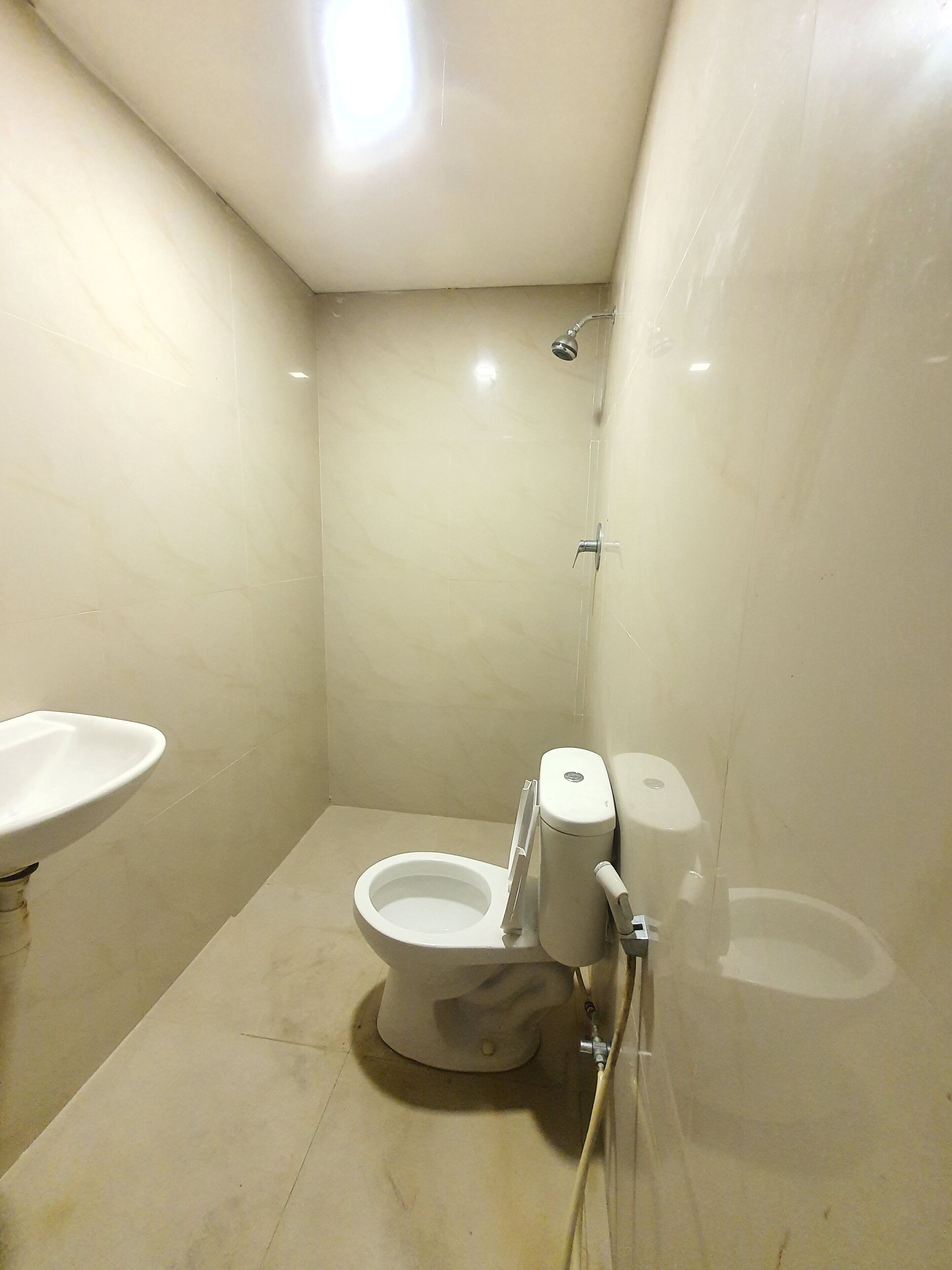 Egy kis, tiszta fürdőszoba, amelyben WC, mosdókagyló és zuhanyzó található.