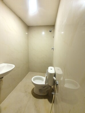 A small, clean bathroom with a toilet, sink, and shower.