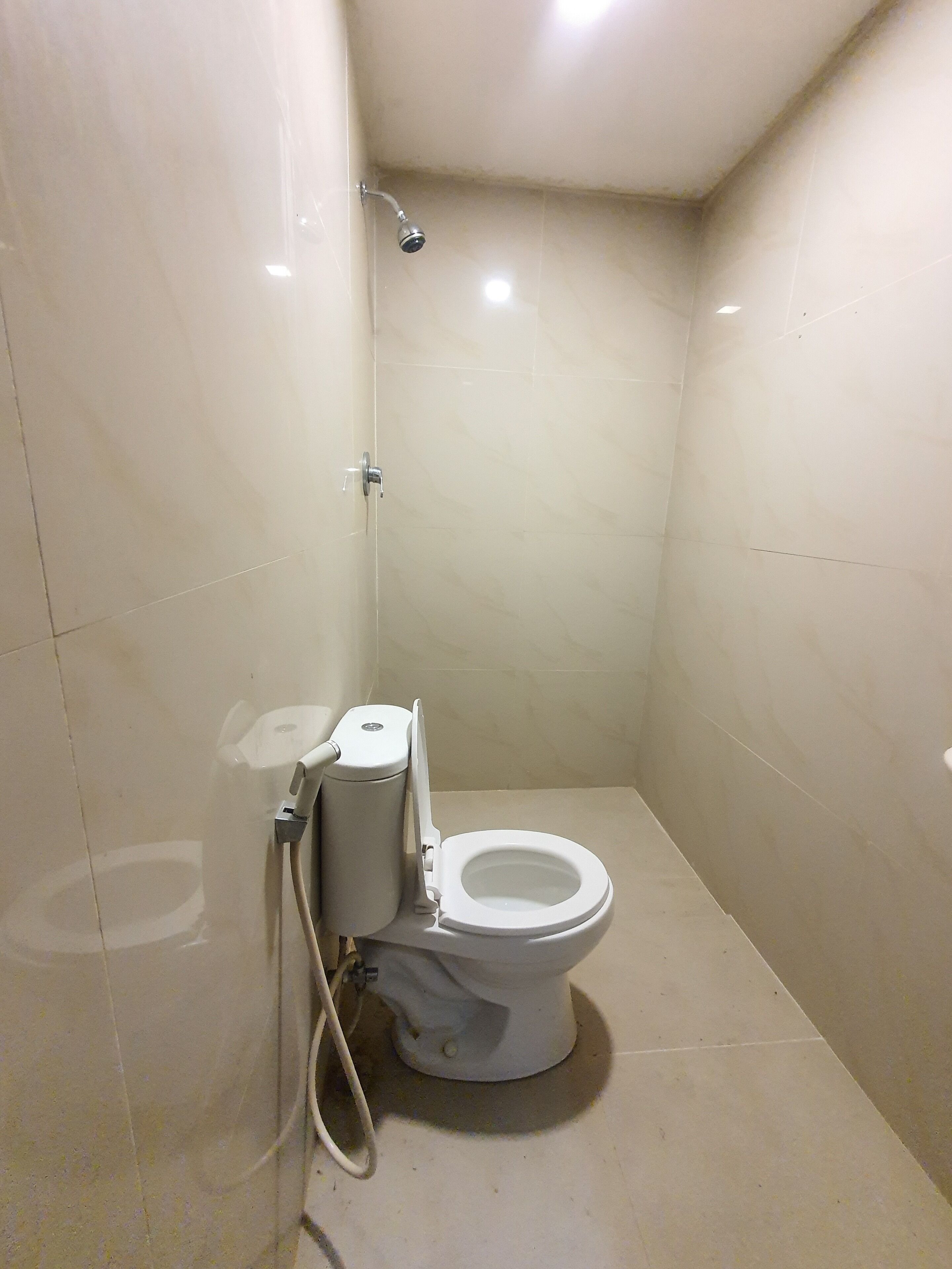 Un baño pequeño y funcional con inodoro, ducha y un dispensador de papel higiénico en la pared.