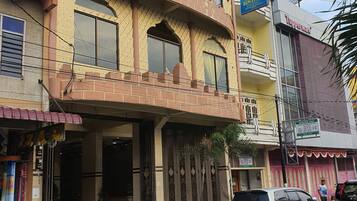 Um edifício de vários andares com fachada amarela, janelas grandes e uma placa com a inscrição 'Hotel Bintang'.