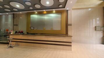 A reception area with a modern design, featuring a large mirror, a reception desk, and a decorative ceiling with circular patterns.