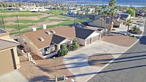 A residential area with houses, a golf course, and a body of water in the background.