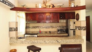 A kitchen with granite countertops, wooden cabinets, a stove, microwave, and a refrigerator. - My little paradise on earth.  (Chicxulub, Progreso, Yucatán)