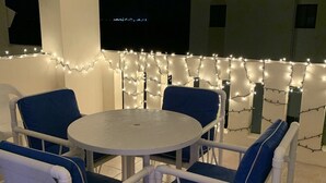An outdoor patio with a round table and blue chairs, surrounded by white pillars and string lights. - My little paradise on earth.  (Chicxulub, Progreso, Yucatán)