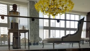A hotel lobby with a marble reception desk, a yellow chandelier, and a view of the cityscape through large windows. - Fun Getaway in the Center of Downtown Miami , available for art Basel (Miami)