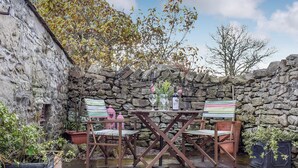 A stone wall with a table and chairs set up for a meal. - 3 bedroom accommodation in Giggleswick, near Settle (Giggleswick, near Settle)