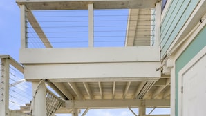 Une terrasse en bois qui mène à un espace abrité offrant une vue sur l’océan.