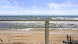 Une vue sur la plage, avec une balustrade en bois et une plage de sable.