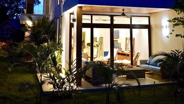 A modern two-story house with a balcony, large windows, and a well-lit interior. - West Bay Golf Club & Villas (Roatan)