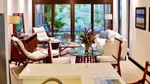 A modern living room with a large window, white furniture, and a hanging light fixture. - West Bay Golf Club & Villas (Roatan)
