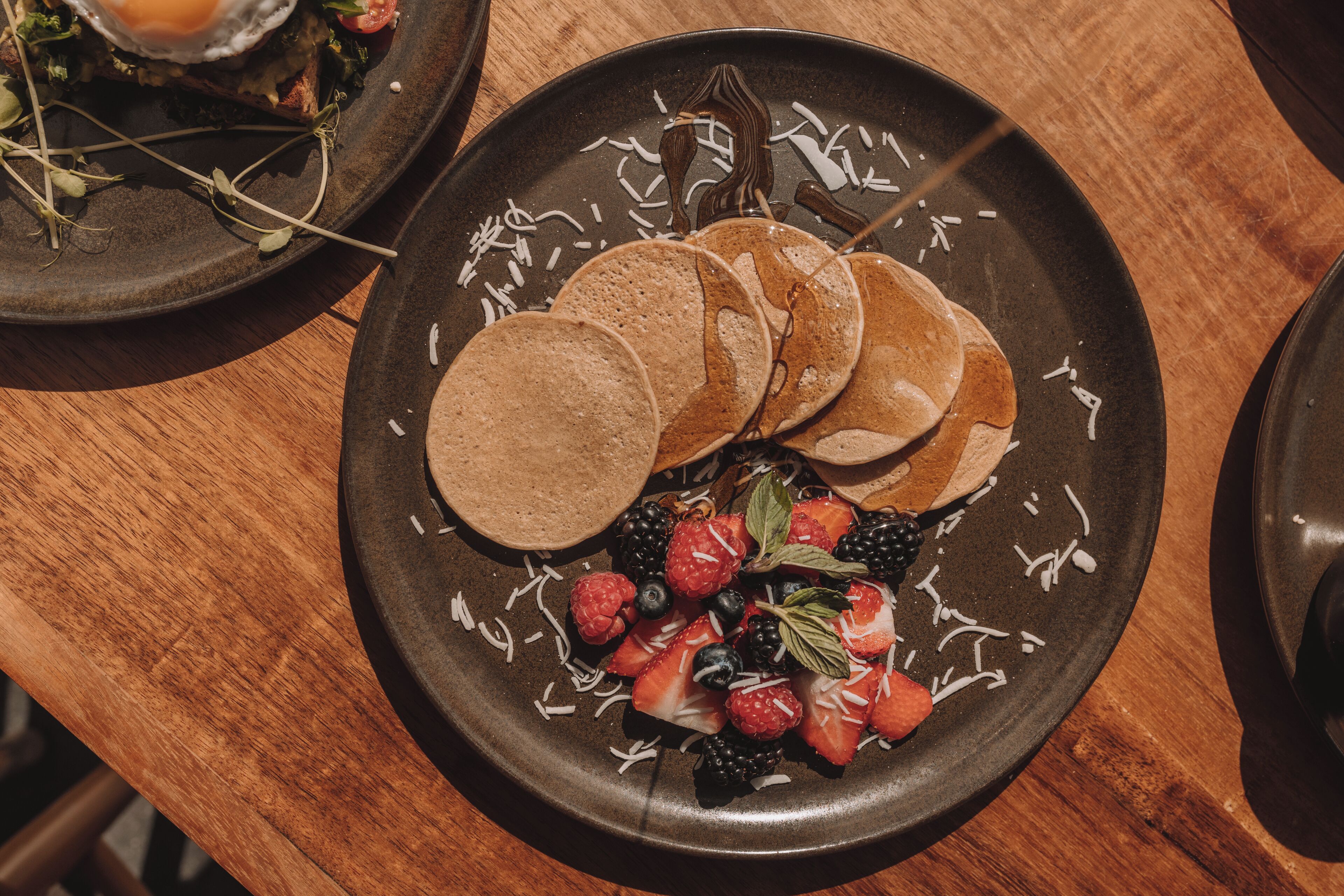 A plate of pancakes with fresh berries and a drizzle of syrup.