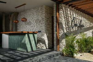 A reception area with a stone wall, a wooden reception desk, hanging pendant lights, and a small garden with plants.