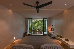 A modern bedroom with a large bed, a ceiling fan, and a view of a patio with outdoor furniture.