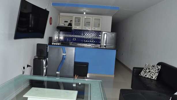 A modern kitchen with blue accents, a black leather sofa, and a glass coffee table. - Las Margaritas (Cali)