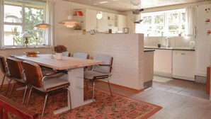 A modern kitchen with white cabinets, a wooden dining table, and a kitchen island. - Amazing home in Blåvand with sauna (Blåvand)