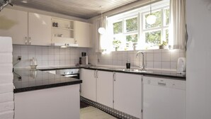 A modern kitchen with white cabinets, a black countertop, and a window providing natural light. - Amazing home in Blåvand with sauna (Blåvand)