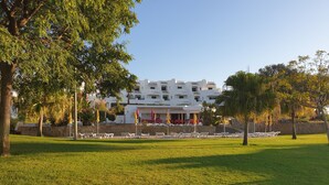 Un hotel con fachada blanca, zona de estar al aire libre y césped bien cuidado.