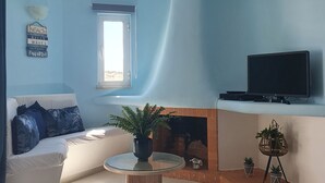 Una sala de estar con sofá, televisión, chimenea y ventana.