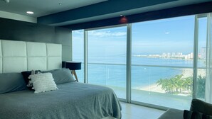 Un dormitorio moderno con una cama grande, una mesita de noche y vista al océano.