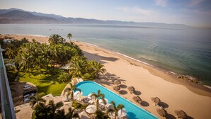 Un resort frente al mar con piscina, palmeras y vistas al océano.