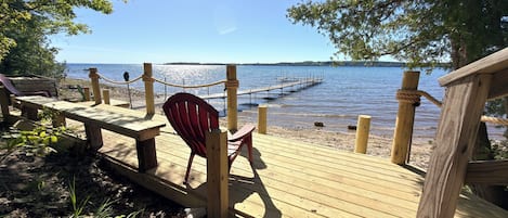 A wooden deck with picnic tables and chairs overlooking a lake.