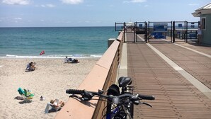 Ein Strand mit einer Holzpromenade, einem Fahrrad und einer Flagge.