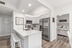 Una cocina moderna con armarios blancos, electrodomésticos de acero inoxidable y una isla de mármol.