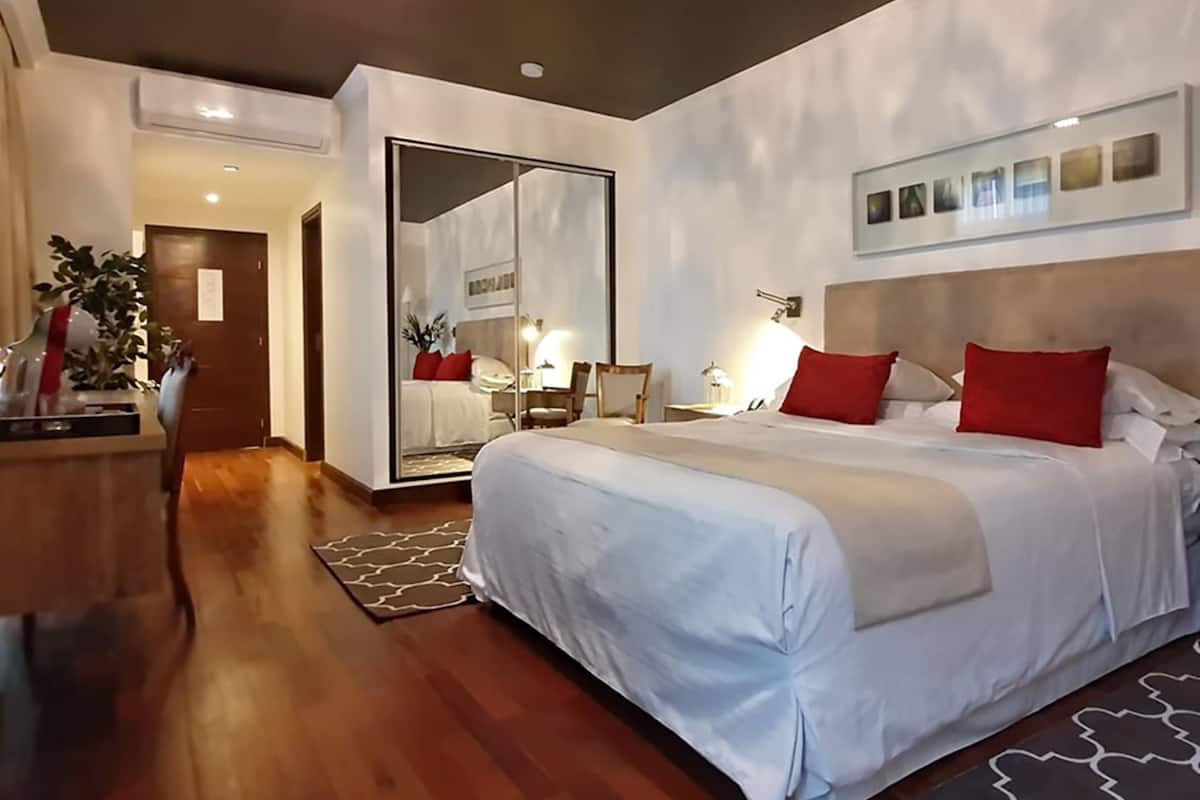 Ein modernes Hotelzimmer mit einem großen Bett, einem Schreibtisch und einem Spiegel.