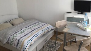A bedroom with a bed, a desk, a chair, a TV, and a water bottle on the desk. - SWEET HOME GOLF OF APREMONT (Apremont)