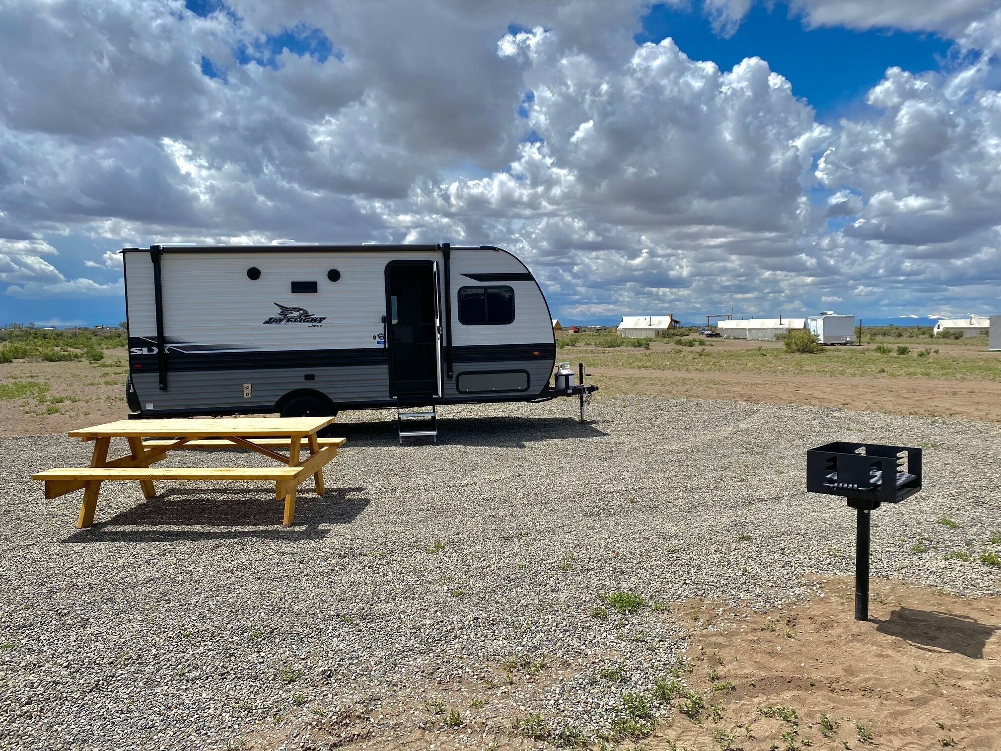 Una caravana Jay Flight estacionada sobre grava, amb una taula de picnic i una bústia a prop.