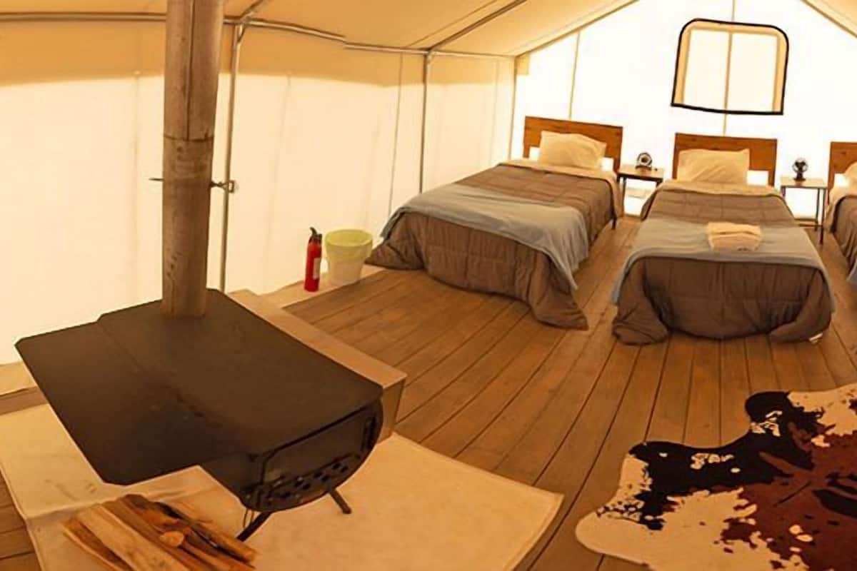 A tented accommodation with two beds, a seating area, and a central table.
