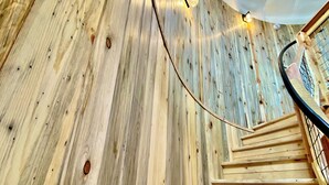 Un escalier en bois au design incurvé, agrémenté de guirlandes lumineuses et surmonté d’un plafond blanc.