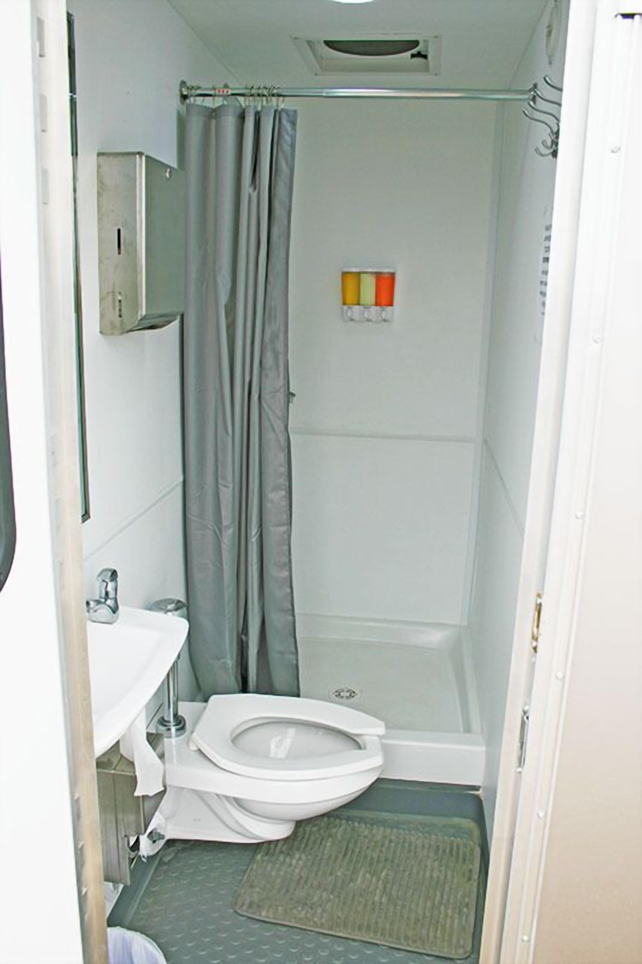 A small, compact bathroom with a toilet, sink, and shower.