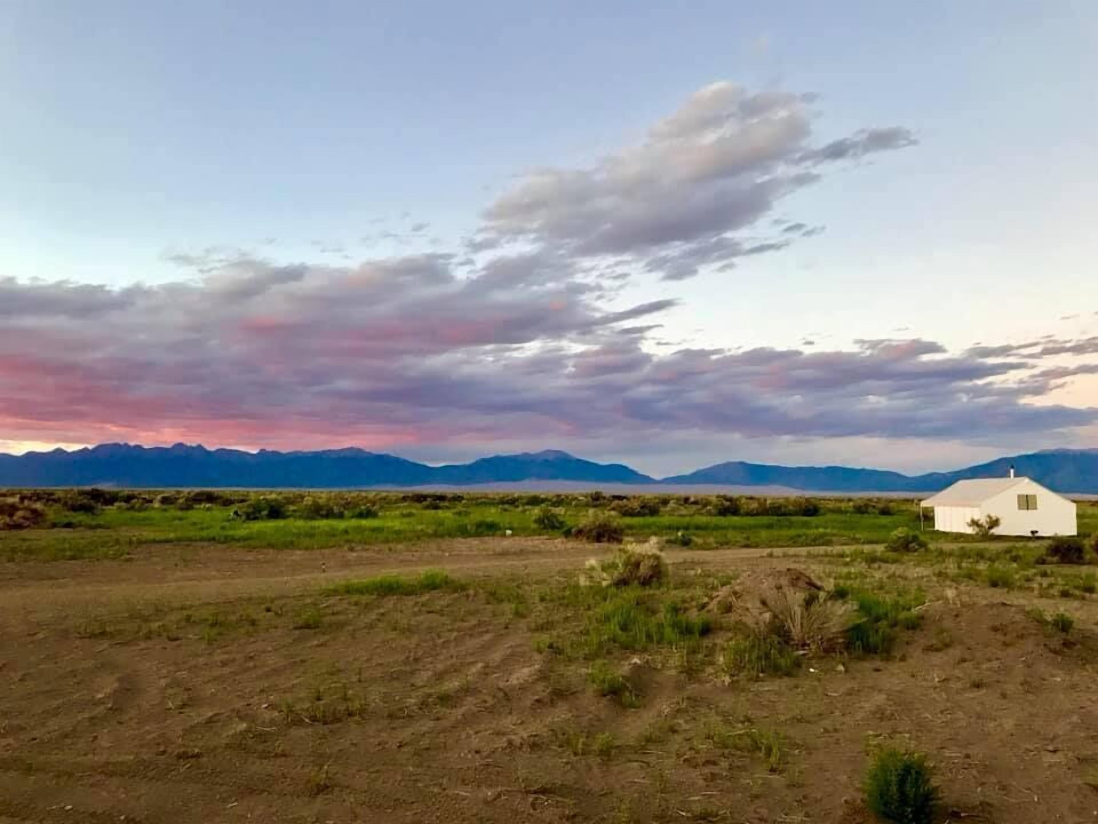 A white building with a flat roof in a rural landscape with mountains in the background.