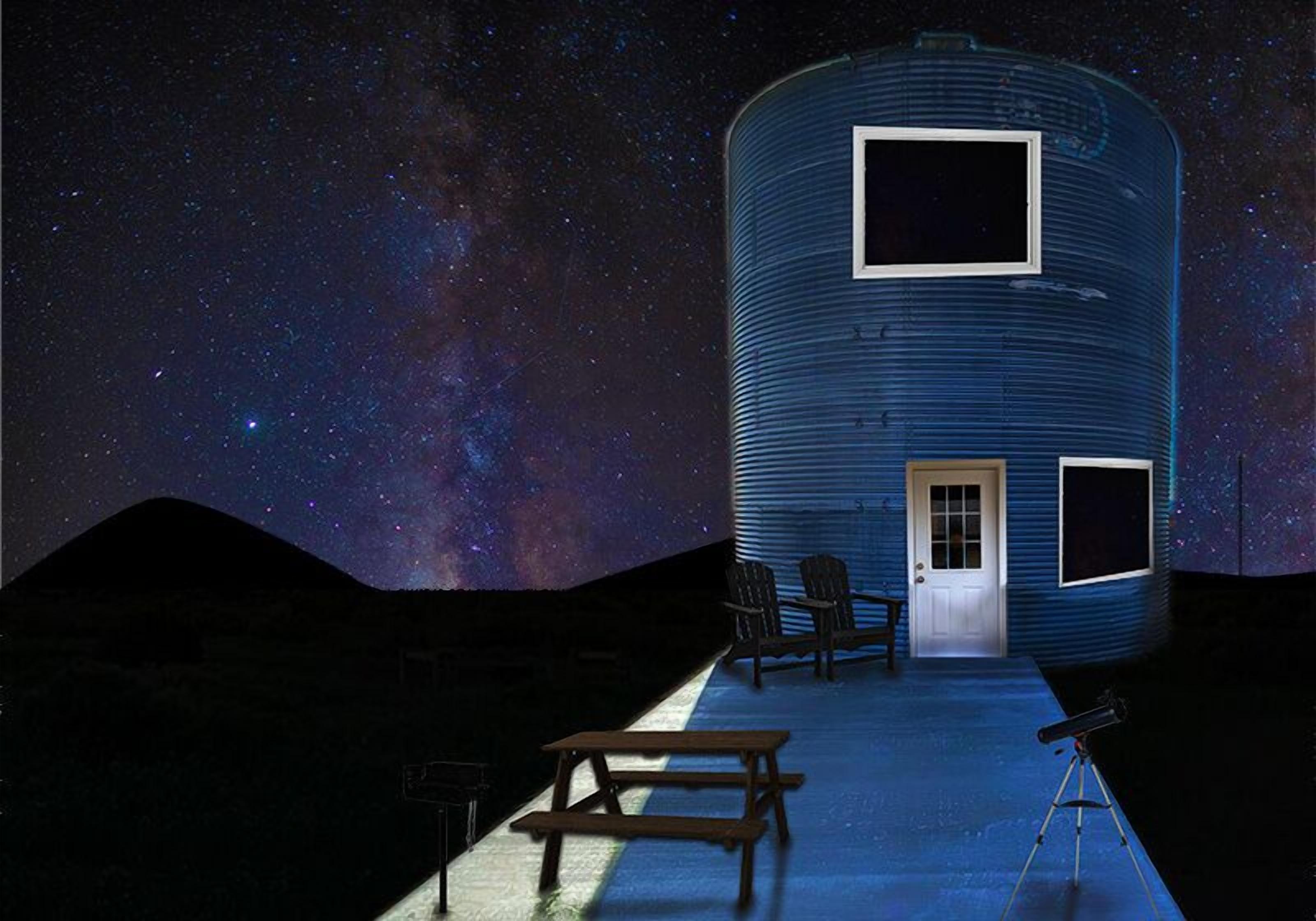 Un edificio cilíndrico con una puerta y ventanas, un telescopio y una mesa de picnic bajo un cielo estrellado.