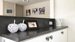 A kitchen counter with wicker baskets, a framed picture, and a white coffee maker.