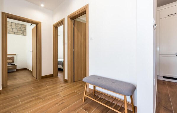 Un couloir avec un plancher en bois, un banc et une armoire.