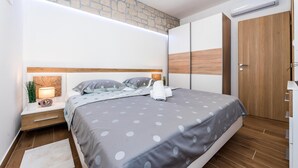 A modern bedroom with a bed, bedside tables, a lamp, and a wooden wardrobe. - Lovely home in Puljane (Puljane)