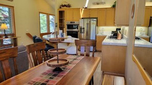 A kitchen with wooden cabinets, a dining table with a placemat, and a built-in oven. - Snowcreek Resort Vacation Rental 955 (Mammoth Lakes)