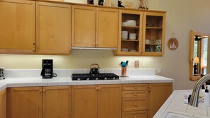 A kitchen with wooden cabinets, a coffee maker, a kettle, and a sink with a faucet.