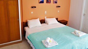 Quarto de hotel com cama, duas mesas de cabeceira, guarda-roupa de madeira e parede com três quadros pequenos.