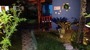 A pathway leading to a reception area with a sign, surrounded by greenery and a wooden pergola. - Pousada Pôr do Sol (Maraú)