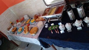 A buffet setup with various food items and utensils. - Pousada Pôr do Sol (Maraú)