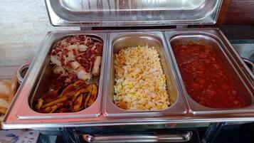 Un buffet avec trois plateaux de nourriture : un avec du bacon et des oignons, un avec des œufs brouillés et un avec du chili.